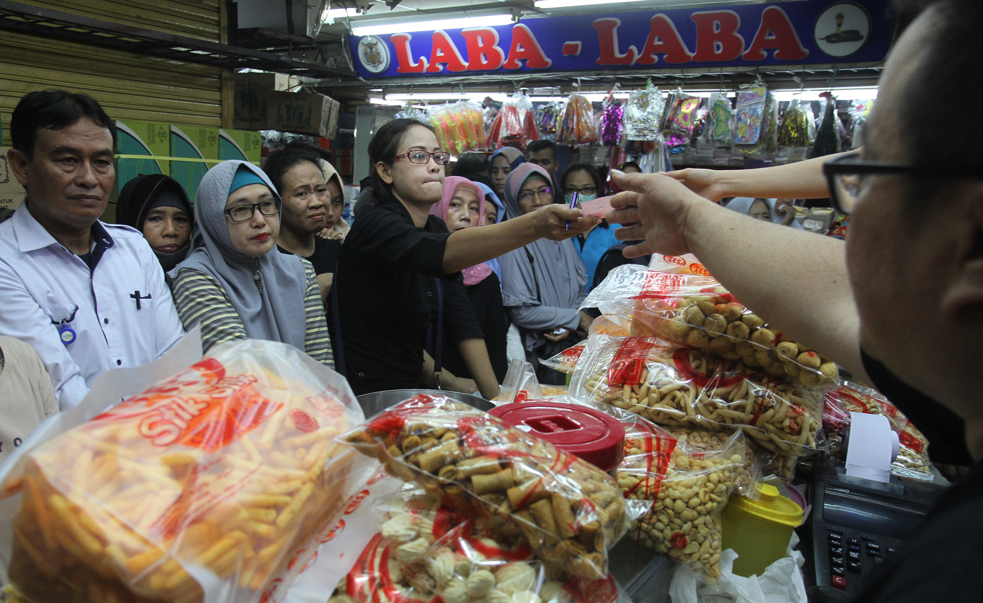 Warga mengantre membeli kue kering di pasar Jatinegara, Jakarta, Kamis (28/3). (Indonesiaglobe/Oke Atmaja)