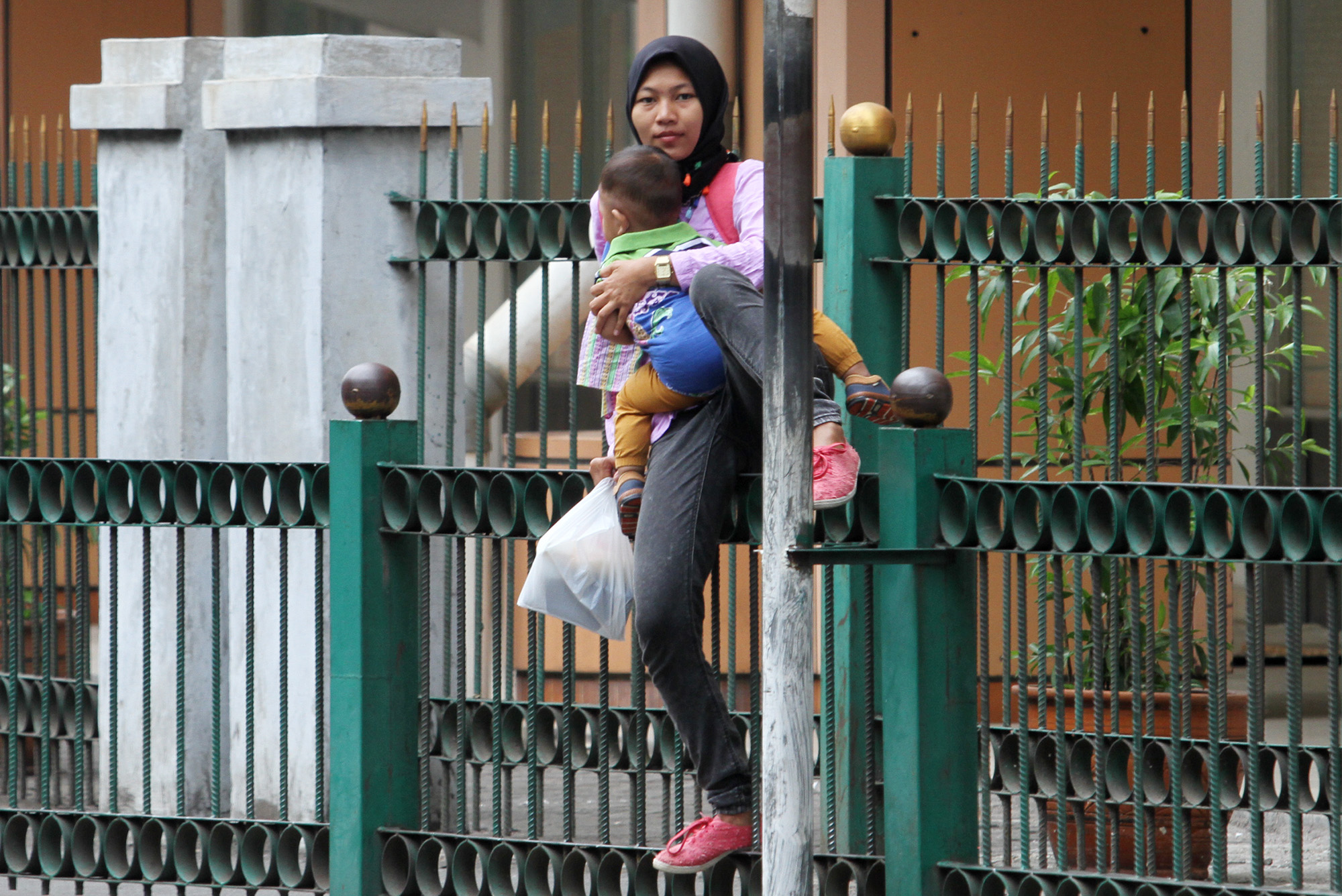 Penumpang KRL melompati pagar pembatas di depan Stasiun Cikini, Jalan Cikini Raya, Jakarta Pusat, Rabu (20/3/2024).  (IndonesiaGlobe/Oke Atmaja)