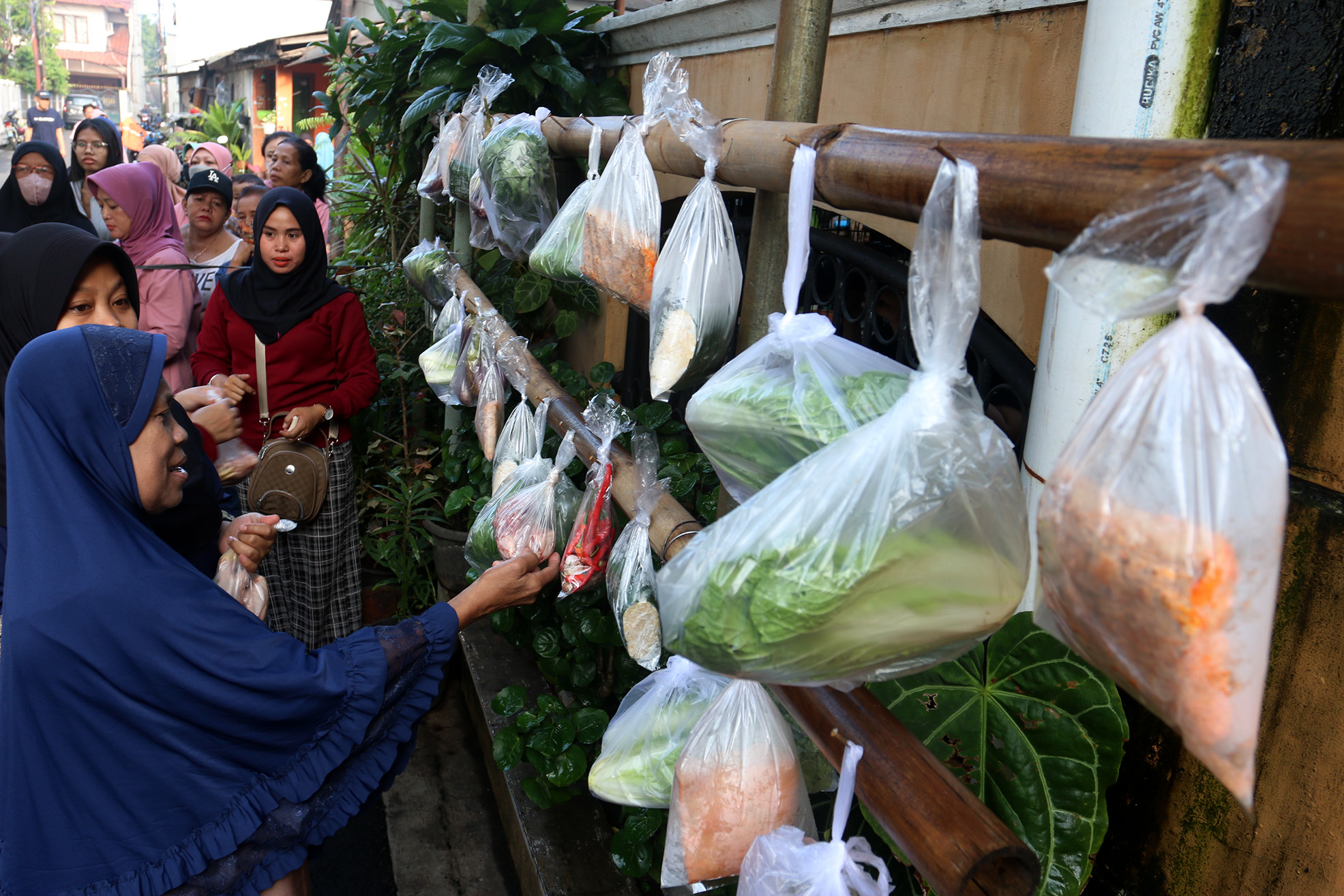 Warga memilih sayur dan pakaian bekas saat bazzar sayuran, bahan makanan dan pakaian layak pakai gratis di Jalan Jati Padang VI, Pasar Minggu, Jakarta, Jumat (29/03/2024).(Indonesiaglobe/Oke Atmaja)