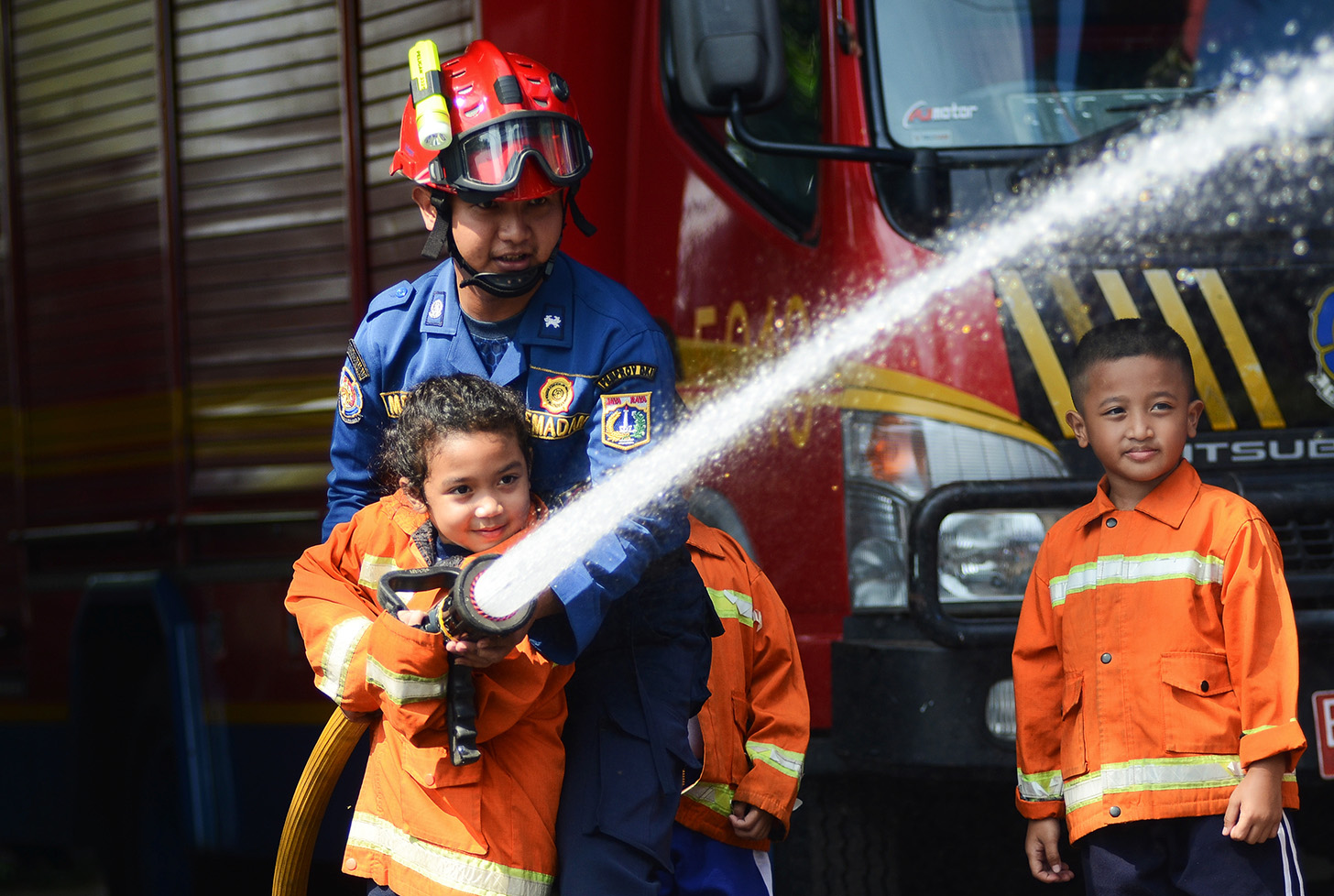 Sejumlah anak TK mencoba menyemprot air dengan selang saat mengunjungi kantor Dinas Pemadam Kebakaran dan Penyalamatan di Jalan Matraman Raya, Jakarta, Sabtu (18/5/2024).  (BeritaNasional.com/Oke Atmaja)
