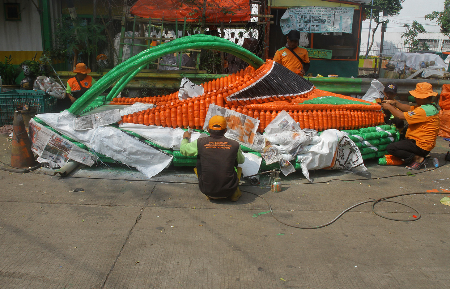 Petugas Unit Penanganan Sampah Badan Air (UPS BA) menyelesaikan pembuatan perahu dari limbah botol plastik di Kwitang, Jakarta, Sabtu (15/7/2024).(BeritaNasional.Com/Oke Atmaja)