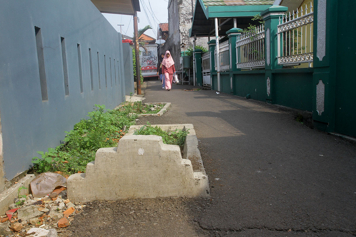 Warga melintas disamping kuburan di gang RT 03 RW 04 Kelurahan Pisangan Timur,Jakarta, Sabtu (13/7/2024) .(BeritaNasional.com/Oke Atmaja)