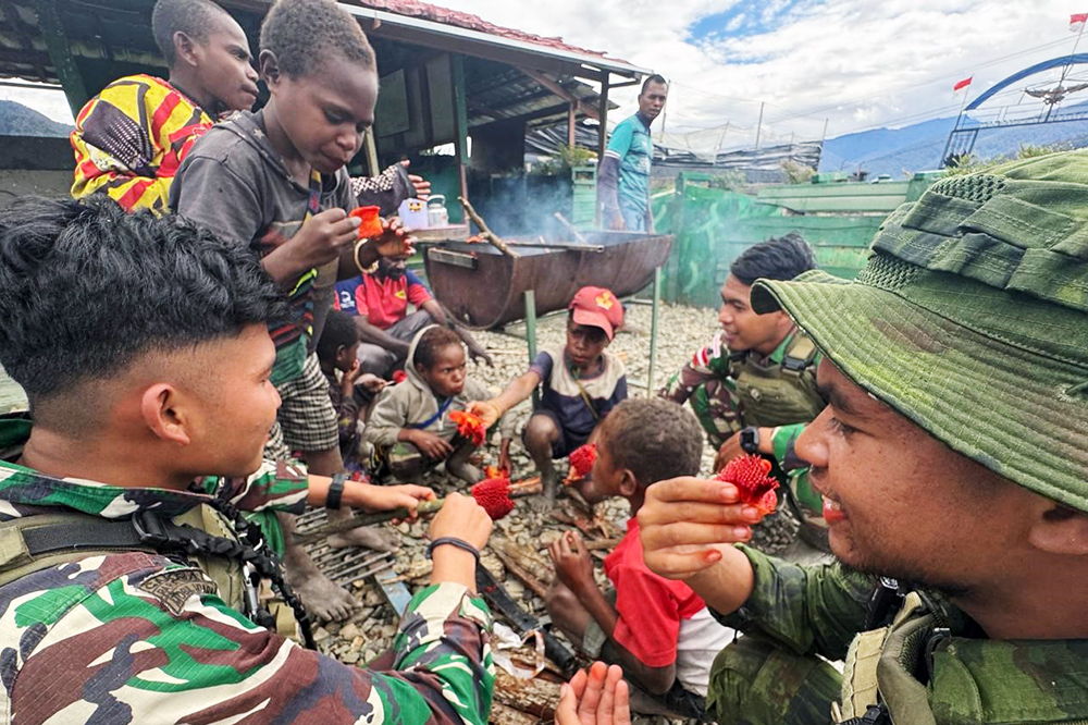 Prajurit Satgas Yonif 509 Kostrad bersama anak-anak Papua berbagi bahagia saat mencoba makan buah merah Papua. (BeritaNasional/HO/Elvis Sendouw)