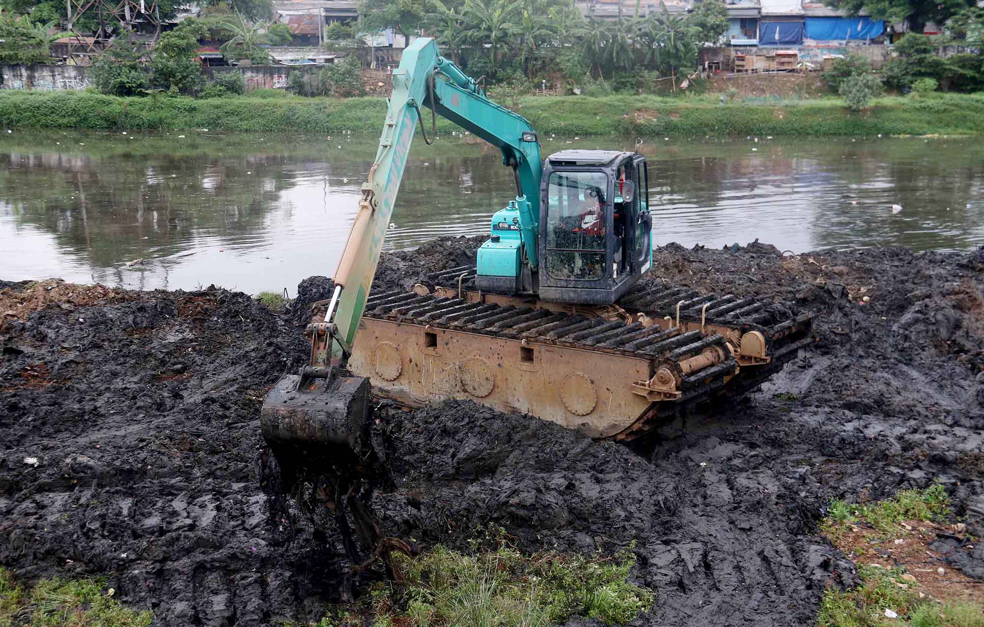 Petugas mengoperasikan alat berat untuk mengeruk lumpur di Sungai Ciliwung, Jakarta, Jumat, (30/8/2024).  (BeritaNasional.com/ Oke Atmaja)