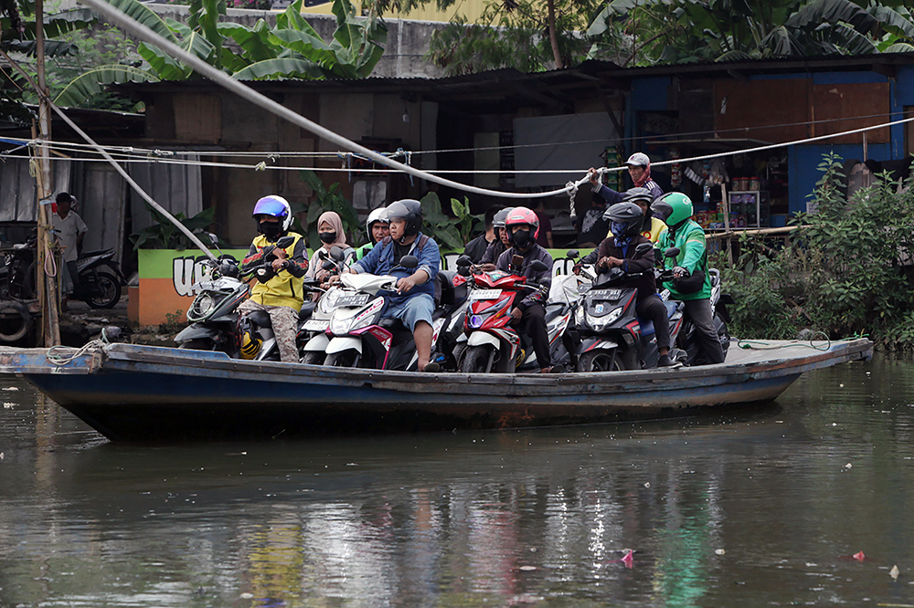 Warga berkendaraan motor saat menyebrang menggunakan perahu eret di Jakarta. (BeritaNasional/Elvis Sendouw)