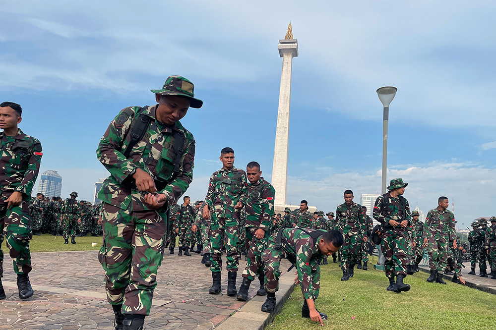 Prajurit Yonif 330 Tri Dharma membersihkan sampah di kawasan lingkungan lapangan silang Monas. (BeritaNasional/HO TNI/Elvis Sendouw)