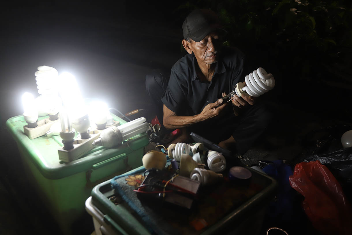 Pak Har (72 Tahun) memperbaiki lampu  bohlam di Lapaknya di Kawasan Kebayoran Lama, Jakarta Selatan, Selasa (15/10/2024).  (BeritaNasional.com/Oke Atmaja)