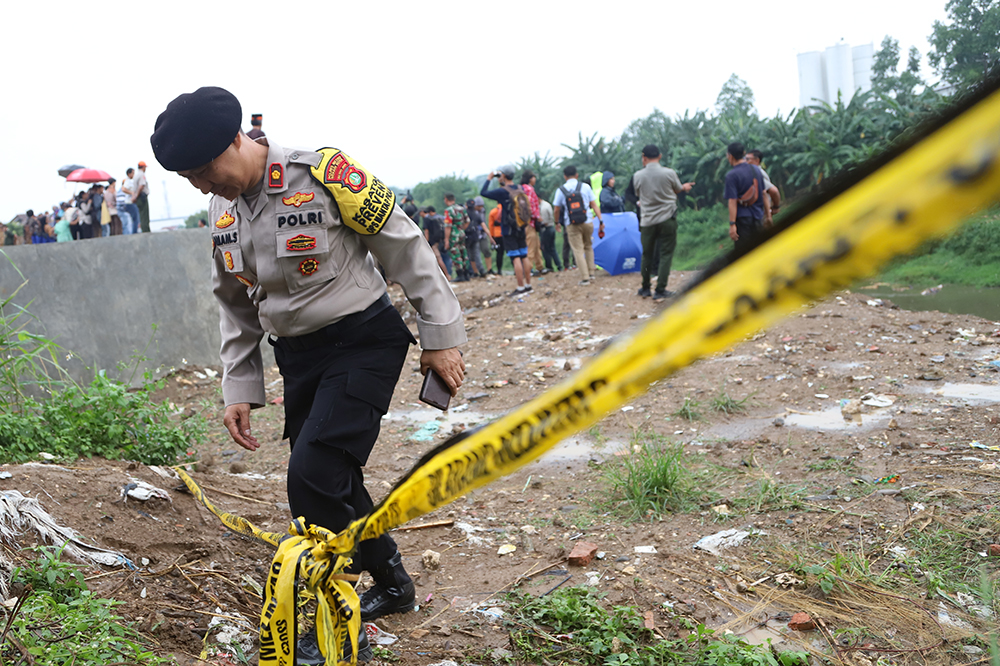 Polisi memasang garis polisi di sekitar tempat penemuan tujuh mayat di Kali Bekasi. (BeritaNasional/Elvis)