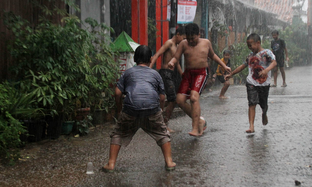 Bocah bermain bola saat hujan deras turun di Menteng Jaya, Jakarta, Minggu (3/11/2024).(BeritaNasional.com/Oke Atmaja)