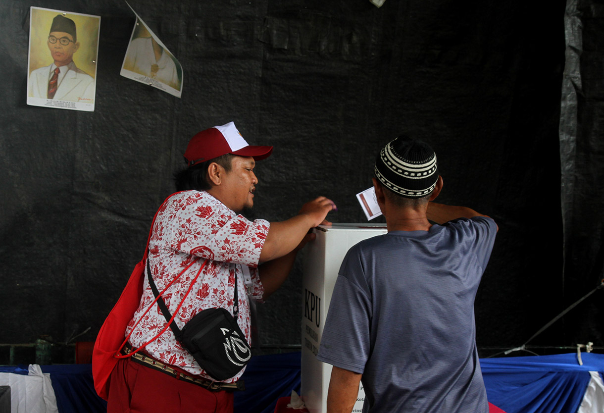 Petugas Kelompok Penyelenggara Pemungutan Suara (KPPS) mengenakan seragam sekolah mengarahkan warga memasukkan surat suara di TPS 05 Petamburan, Tanah Abang, Jakarta, Rabu (27/11/2024).(BeritaNasional.com/Oke Atmaja)