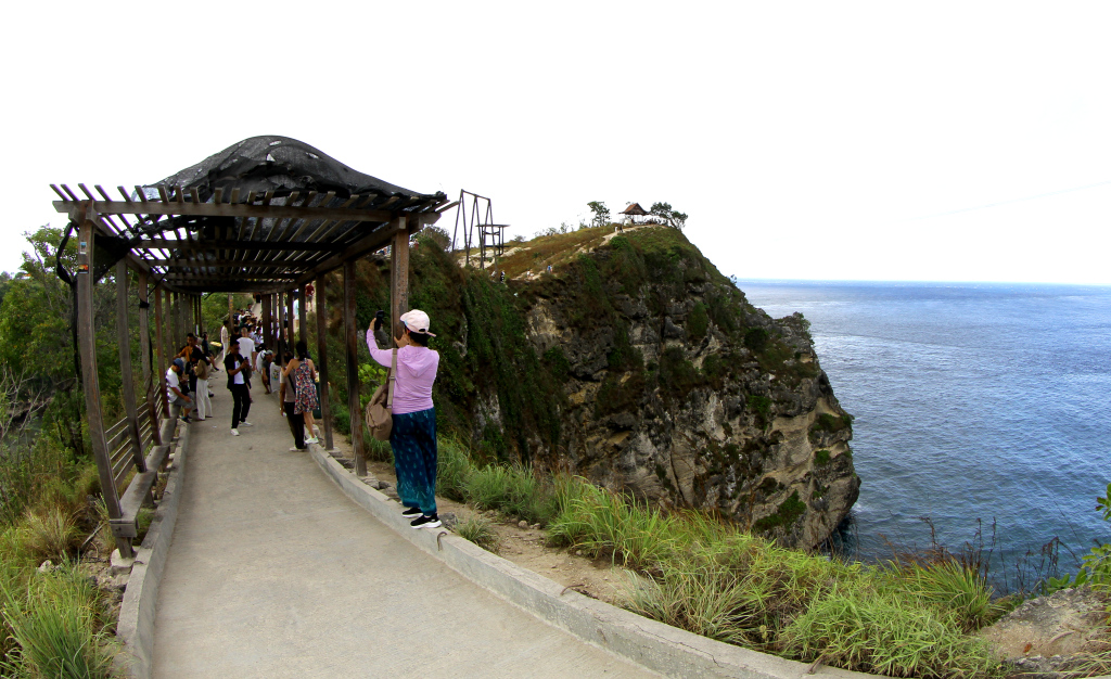 Pengunjung berfoto berlatar pantai Diamond Beach di Nusa Penida, Bali. (BeritaNasional.Com/Oke Atmaja)