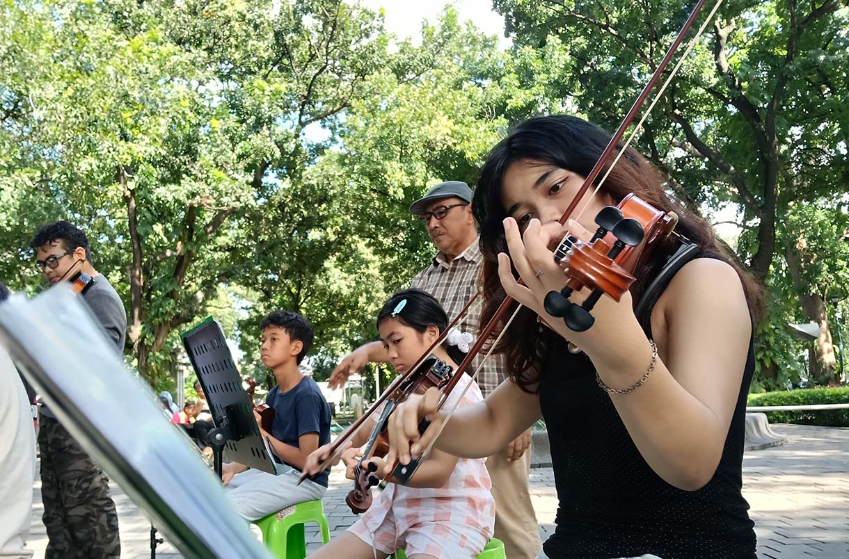 Warga bermain alat musik biola di Taman Suropati, Jakarta, Minggu (19/1/2024).  (BeritaNasional.com/Oke Atmaja)