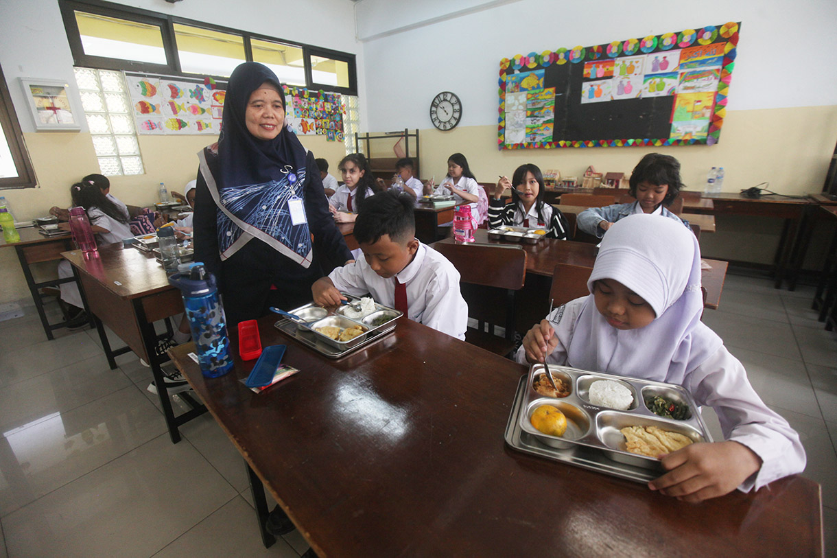 Murid menyantap makanan bergizi gratis di SD Barunawati Slipi, Jakarta, Senin (6/1/2025).(BeritaNasional.com/Oke Atmaja)