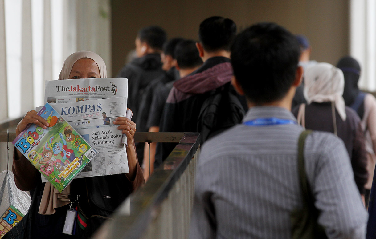 Seorang penjual koran menawarkan daganganya saat berjualan di Jembatan Penyebrangan Orang Halte Transjakarta Jenderal Sudirman, Jakarta, Rabu (08/01/2025).(BeritaNasional.com/Oke Atmaja)