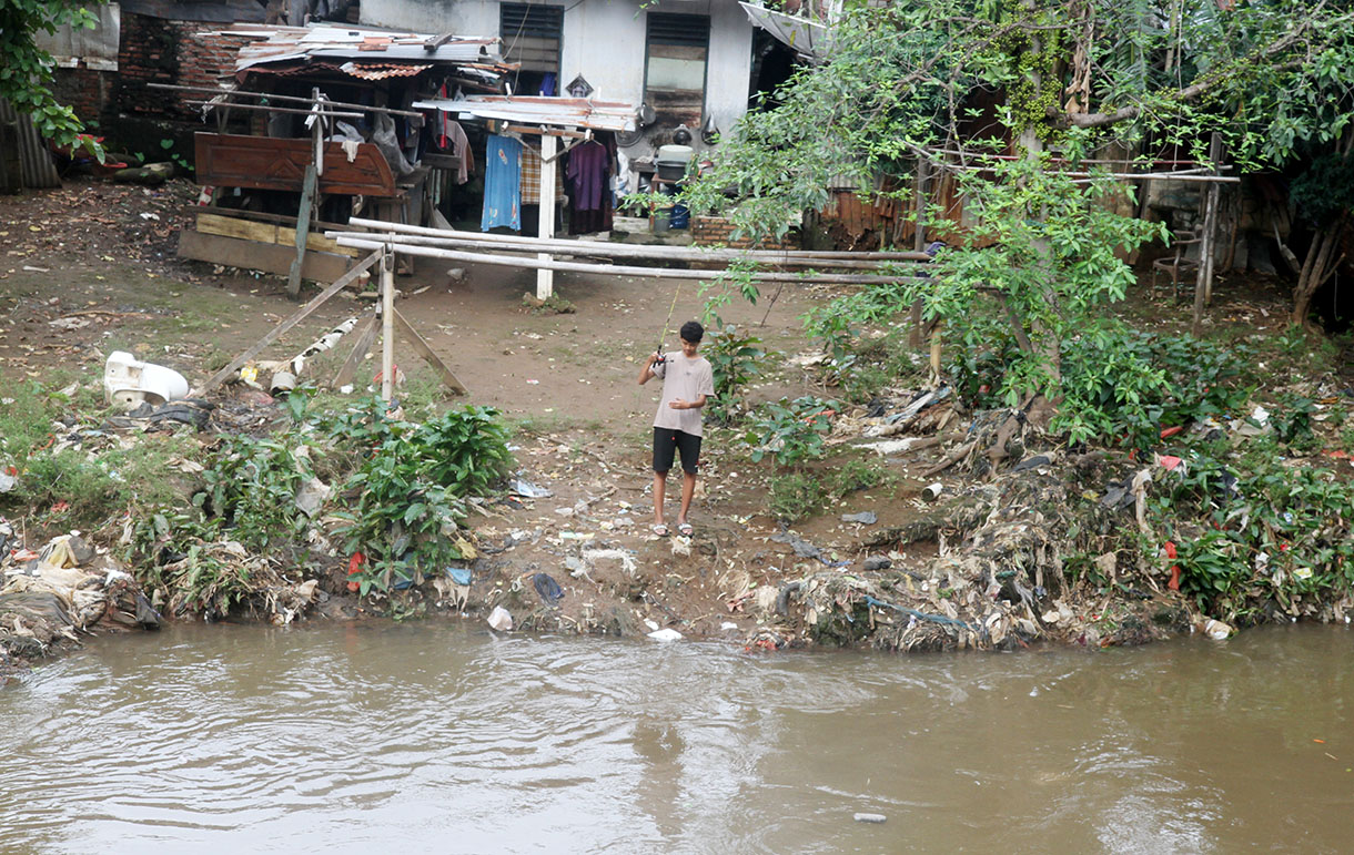 Warga memancing di aliran sungai Ciliwung kawasan Manggarai, Jakarta, Selasa (4/2/2025).(Beritanasional.com/Oke Atmaja)