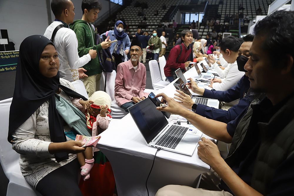 Pekerja Bank melayani warga yang ingin menukarkan uang baru di Jakarta. (BeritaNasional/Elvis Sendouw)