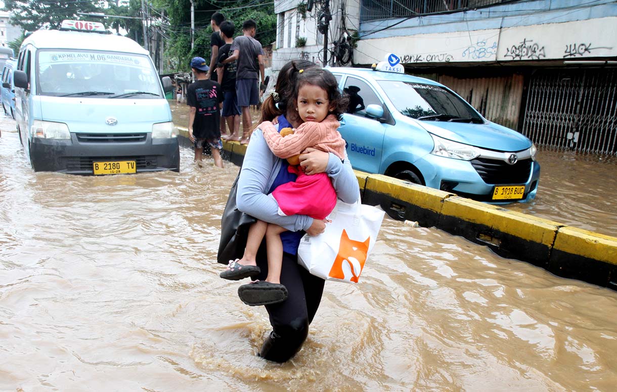 Warga melintasi banjir yang merendam rumah makan di jalan Jatinegara Barat, Jakarta, Selasa (4/3/2025).  (Beritanasional.com/Oke Atmaja)