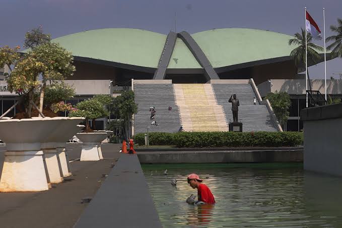 Seorang pekerja membersihkan kolam di depan gedung DPR (BeritaNasional/Elvis)