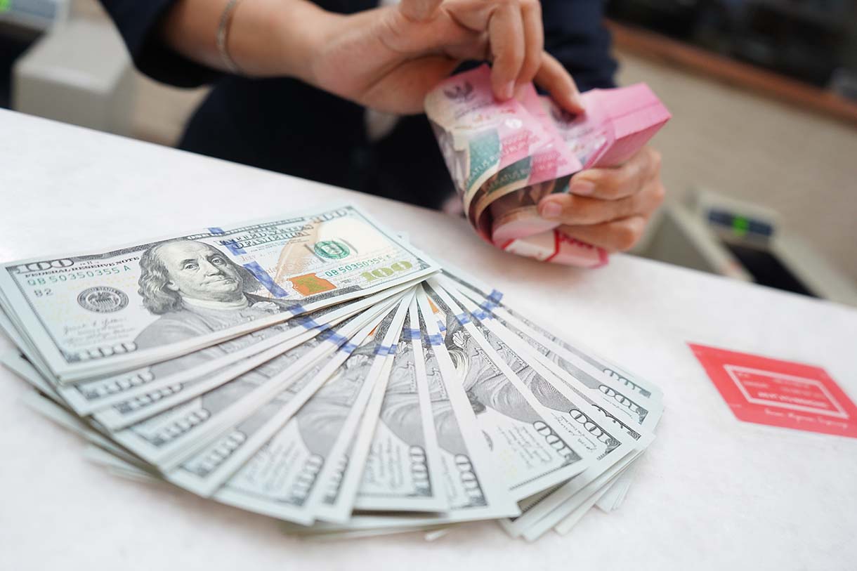 Petugas menunjukan uang pecahan dolar AS dan rupiah di gerai penukaran mata uang asing, Jakarta, Selasa (8/4/2025). (Beritanasional.com/Oke Atmaja)