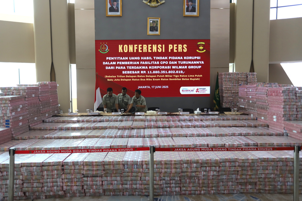 Petugas merapikan barang bukti uang sitaan saat konferensi pers kasus korupsi ekspor crude palm oil (CPO) di Gedung Bundar Jampidus Kejaksaaan Agung (Kejagung), Jakarta, Selasa (17/6/2025). (Beritanasional.com/Oke Atmaja)