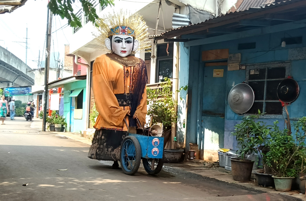 Pengamen ondel-ondel mengamen di perkampungan kawasan Menteng, Jakarta, Rabu (11/6/2025). (Beritanasional.com/Oke Atmaja)