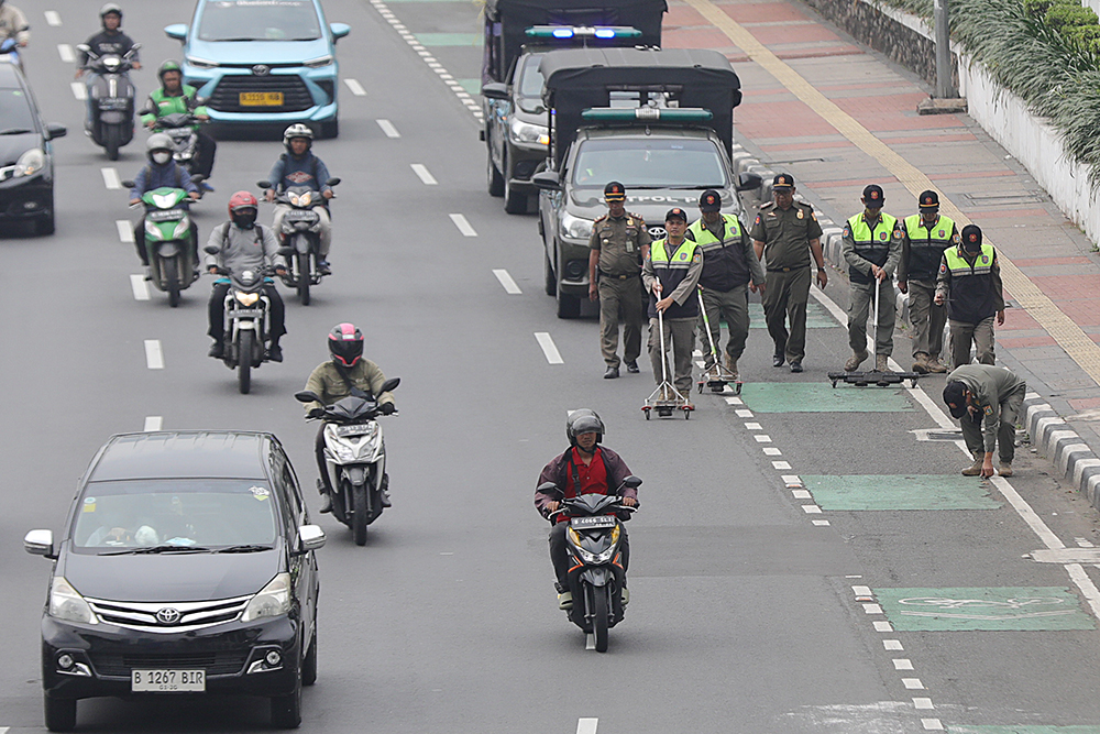 Petugas Satpol PP membersihkan ranjau paku di jalan protokol. (BeritaNasional/Elvis Sendouw)