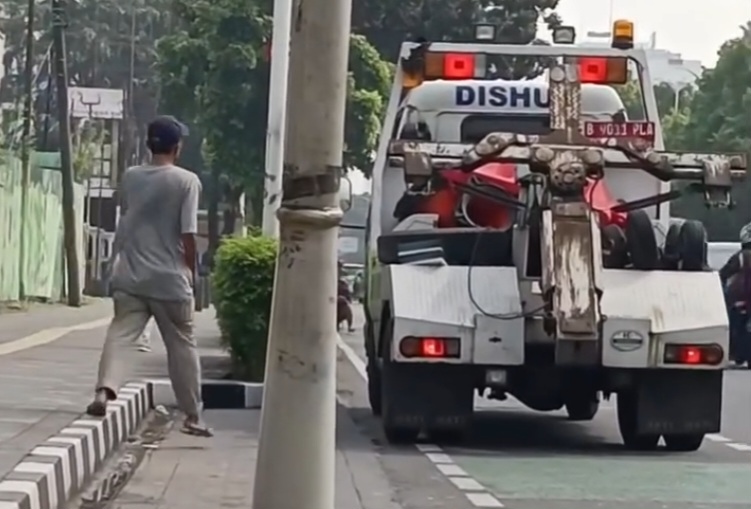 Seorang pria jalan menuju mobil Dishub DKI untuk memberikan rokok ke petugas tersebut. (BeritaNasional/instagram)