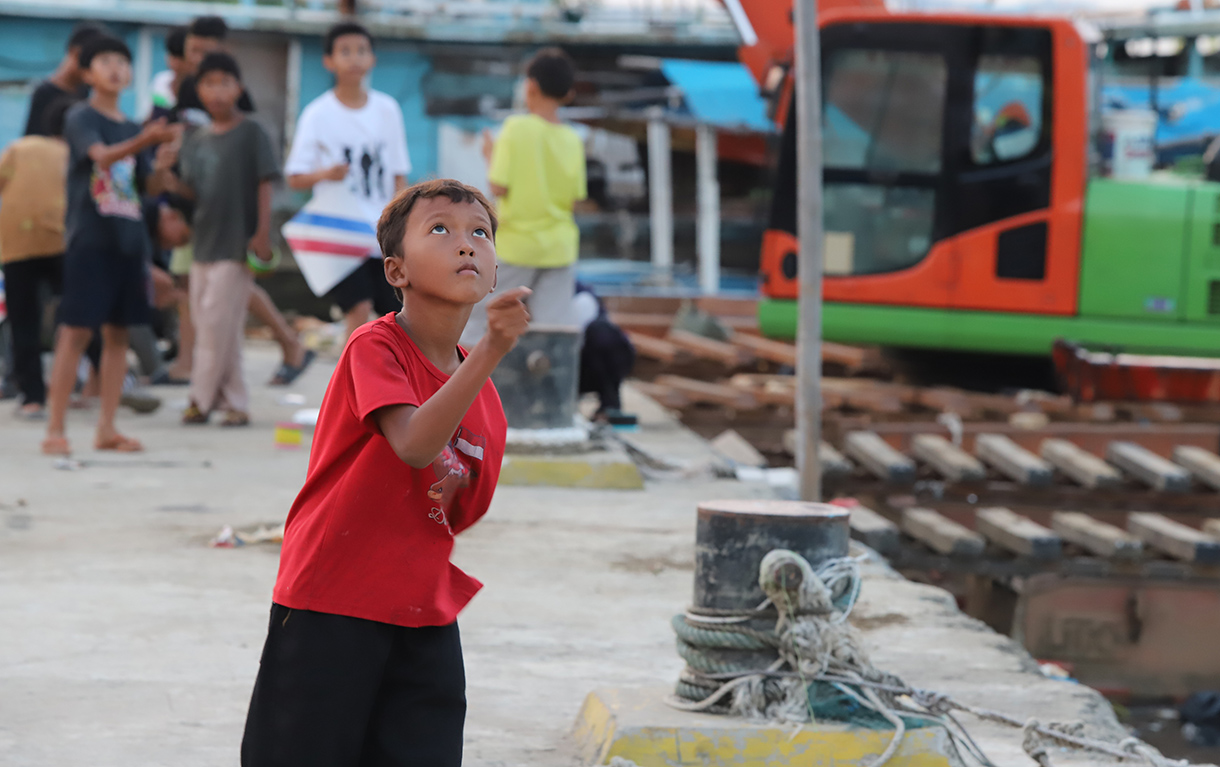 Anak-anak bermain layang-layang di dermaga muara angke, Jakarta, Minggu (13/7/2025).  (Beritanasional.com/Oke Atmaja)