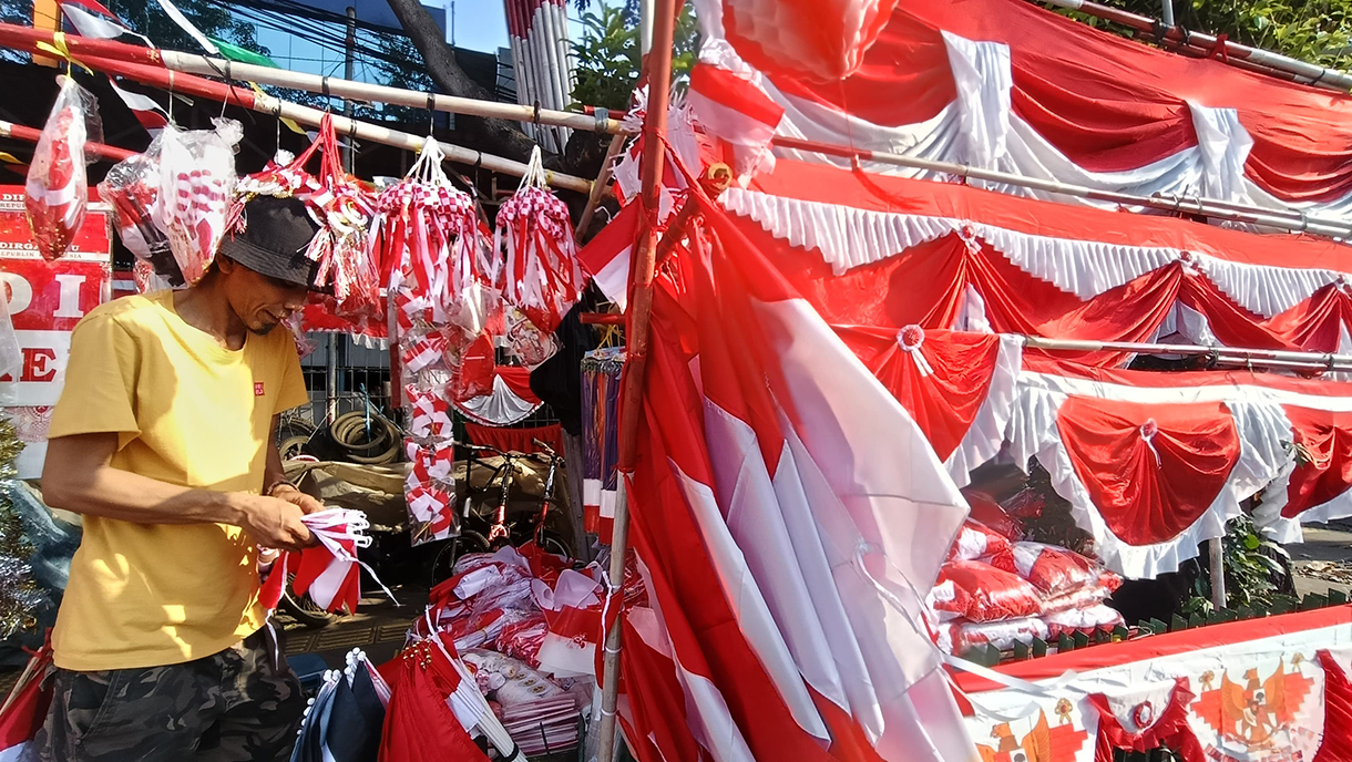 Pedagang musiman bendera dan hiasan bernuansa merah putih menata barang jualannya di pinggir jalan Jatinegara,Rabu (30/7/2025).   (Beritanasional.com/Oke Atmaja)