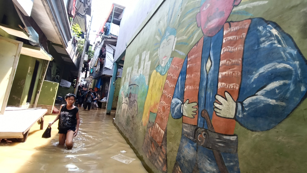 Warga melintasi banjir di Kebon Pala, Jatinegara, Jakarta Timur, Senin (7/7/2025).  (Beritanasional.com/Oke Atmaja)