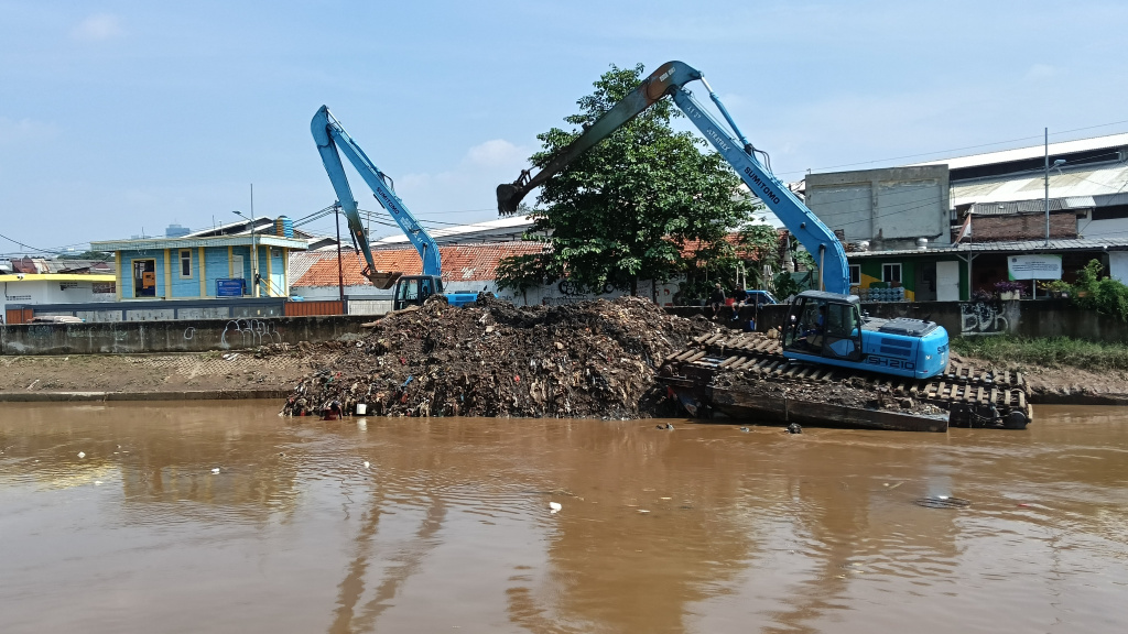 Petugas Dinas Sumber Daya Air mengoperasikan alat berat untuk mengeruk endapan lumpur di Kali Ciliwung, Kampung Melayu, Jakarta Timur, Selasa (8/7/2025).  (Beritanasional.com/Oke Atmaja)