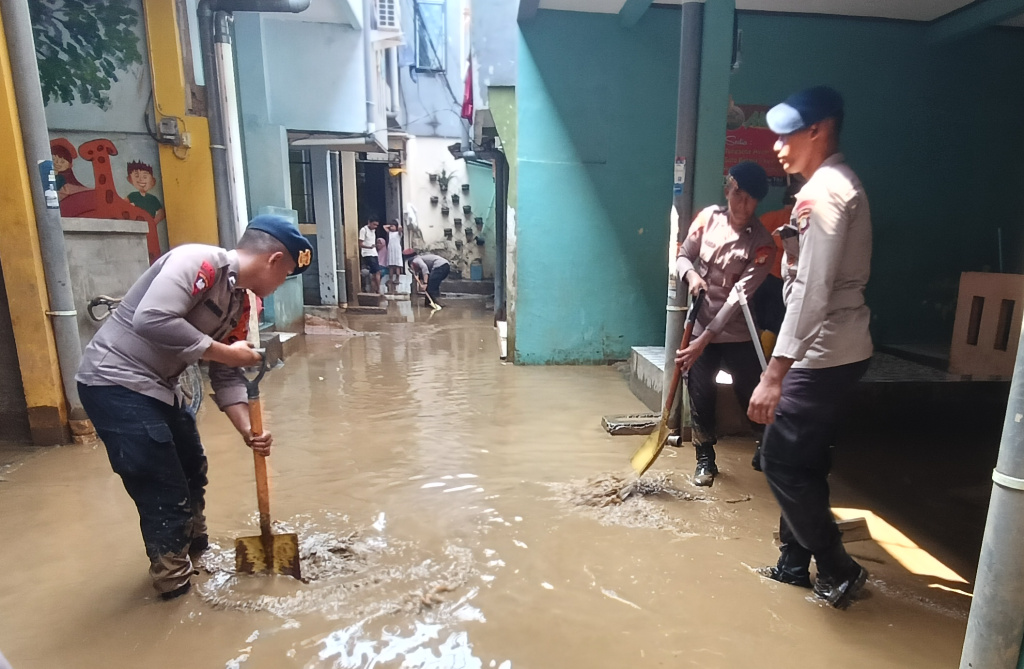 Sejumlah personel kepolisian membantu bersihkan rumah  warga yang terkena banjir di Kebon Pala, Jatinegara, Jakarta Timur (Jaktim), Senin (7/7/2025). (Beritanasional.com/Oke Atmaja)
