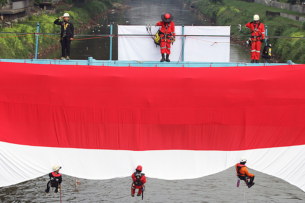Petugas gabungan mengibarkan Bendera Merah Putih berukuran raksasa di sungai Ciliwung. (BeritaNasional/Elvis Sendouw)
