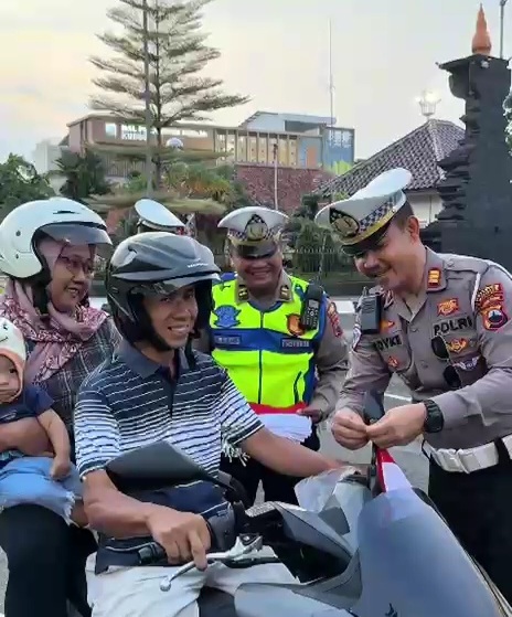 Polisi memasangi bendera Merah Putih di kendaraan warga