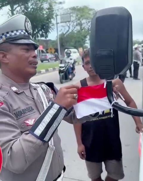 Polantas membagikan bendera Merah Putih kepada pengendara. (Foto/Istimewa)