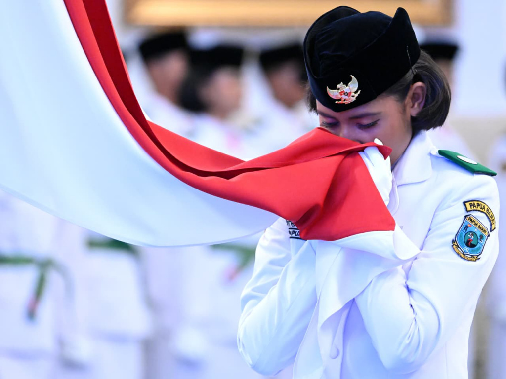Anggota Paskibraka 2025 asal Papua Barat Ritha Lovely CF Ayomi mencium Bendera Merah-Putih dalam upacara pengukuhan Paskibraka Tingkat Pusat 2025 di Istana Negara, Jakarta, Sabtu (16/8/2025).  (Beritanasional.com/ Biro Pers)