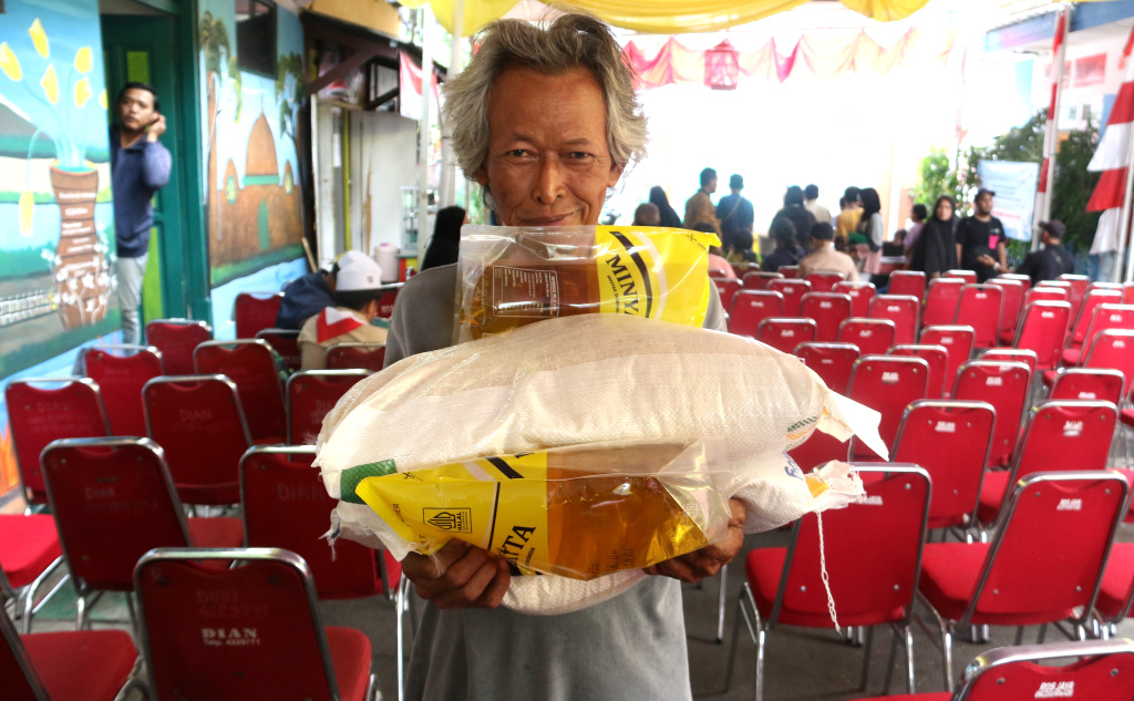 Warga memikul beras usai mengambil bantuan pangan gratis di Balai RW 03 Kelurahan Menteng, Jakarta, Rabu, (12/11/2025). (Berita nasional.com/Oke Atmaja)