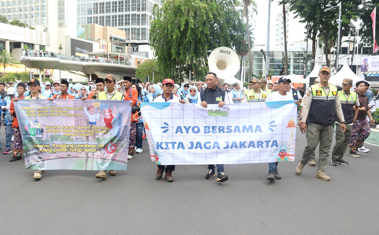 Sejumlah peserta membawa spanduk berisi imbauan untuk menjaga kebersihan dan ketertiban saat mengikuti pawai pada Hari Bebas Kendaraan Bermotor (HBKB) di kawasan Bundaran HI, Jakarta Pusat, Minggu (16/11/2025).(Beritanasional.com/Oke Atmaja)