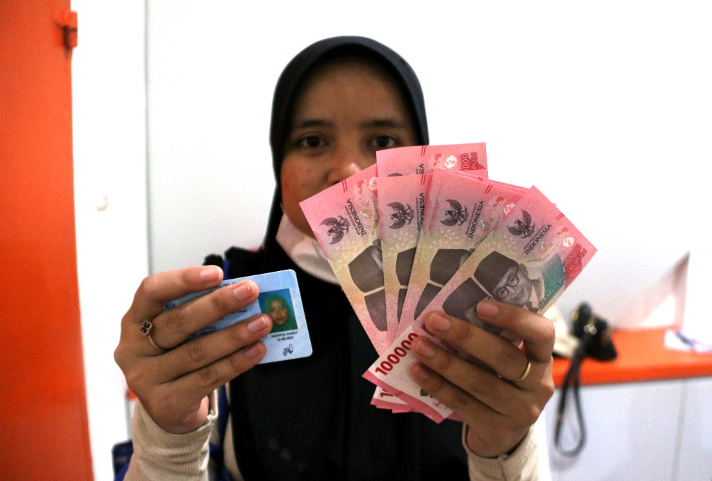 Warga penerima manfaat Bantuan Langsung Tunai Sementara Kesejahteraan Rakyat (BLTS Kesra) menunjukan uang usai melakukan pencairan dana di Kantor Pos Kebon Jeruk, Jakarta, Kamis (27/11/2025). (Beritanasional.com/Oke Atmaja)