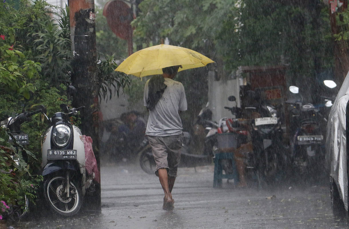 Warga menggunakan payung menerobos hujan di Jalan Menteng Jaya, Jakarta, Selasa (18/11/2025). (Beritanasional.com/Oke Atmaja)