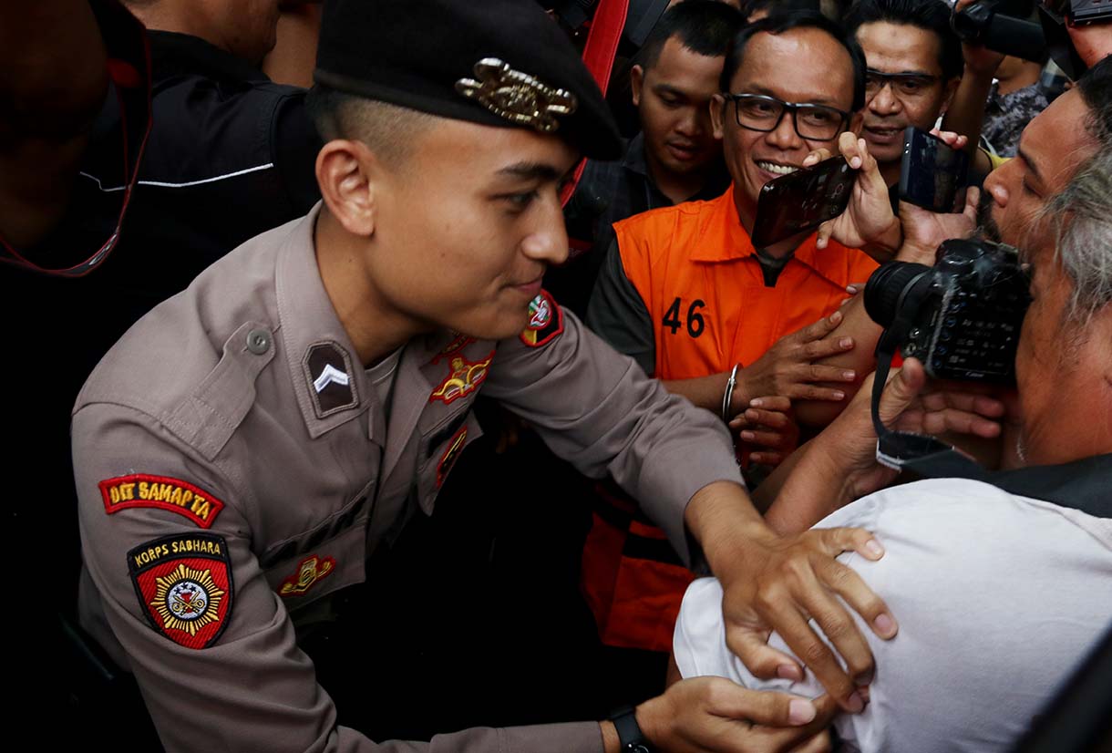 Tersangka kasus dugaan suap dan gratifikasi Bupati Lampung Tengah periode 2025-2030 Ardito Wijaya (kiri) berjalan menuju mobil tahanan usai dihadirkan dalam konferensi pers di Gedung Merah Putih KPK, Jakarta, Kamis (11/12/2025). (Beritanasional.com/Oke Atmaja)