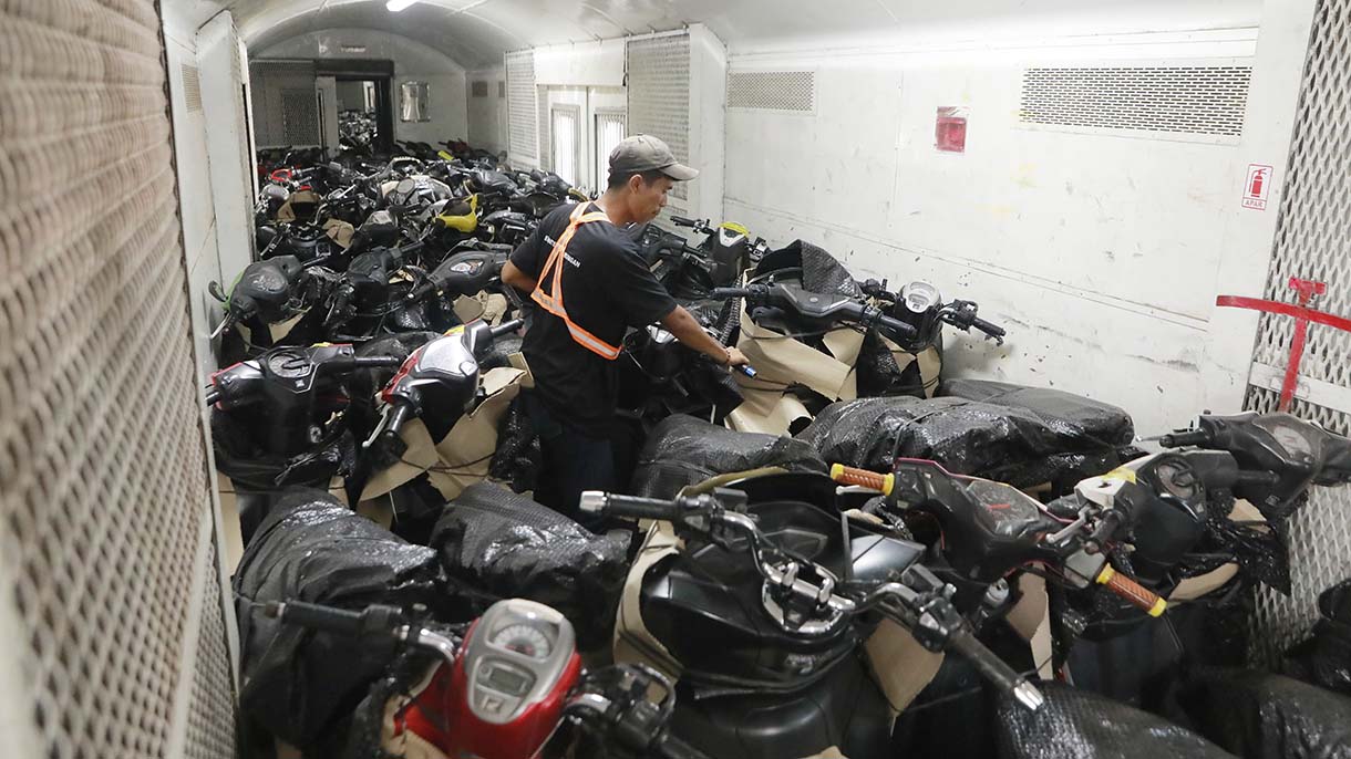 Petugas merapikan motor penumpang peserta layanan Angkutan Motor Gratis dengan Kereta Api (Motis) di dalam gerbong kereta api di Stasiun Pasar Senen, Jakarta, Selasa (23/12/2025).  (Beritanasional.com/Oke Atmaja)