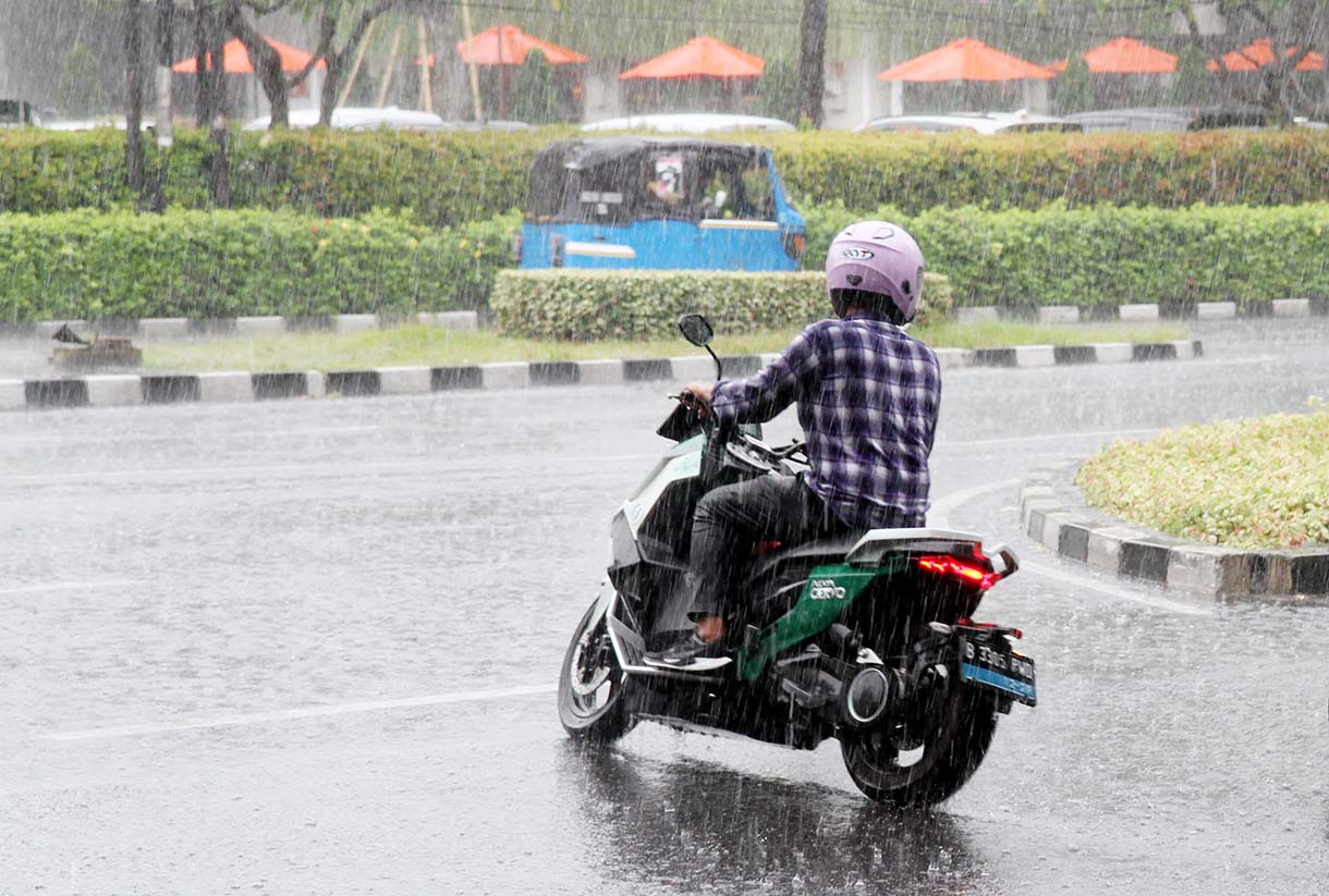 Warga menerobos hujan sambil berkendara. (BeritaNasional/Oke Atmaja)