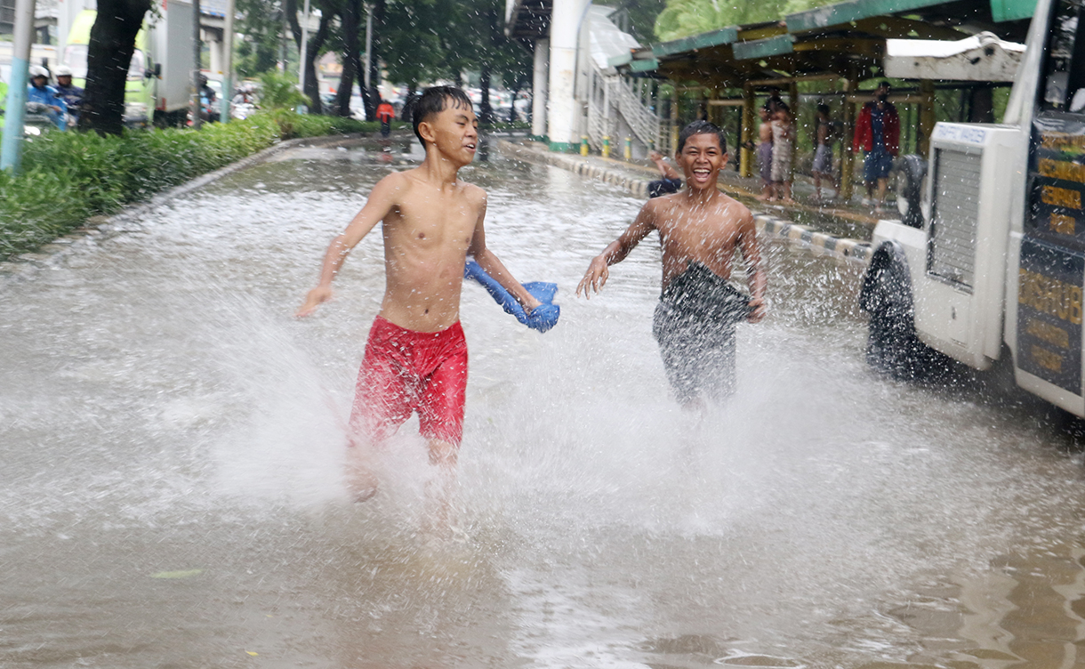 Seorang anak bermain di genangan air yang membanjiri jalan sekitar Cempaka Putih, Jakarta, Kamis(22/1/2026).(Beritanasional.com/Oke Atmaja)