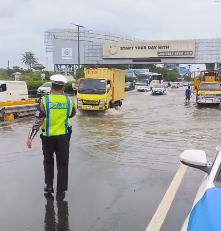 Polisi lalu lintas mengatur kendaraan melewati ruas jalan yang digenangi air. (BeritaNasional/Bachtiarudin)