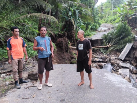 Warga berdiri di jalan yang terputus akibat tanah longsor di Halmahera Utara Maluku Utara. (BeritaNasional/BNPB)