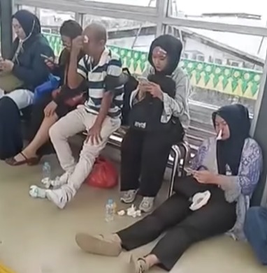 Penumpang bus Transjakarta yang luka duduk di halte bus. (BeritaNasional/tangkapan layar)