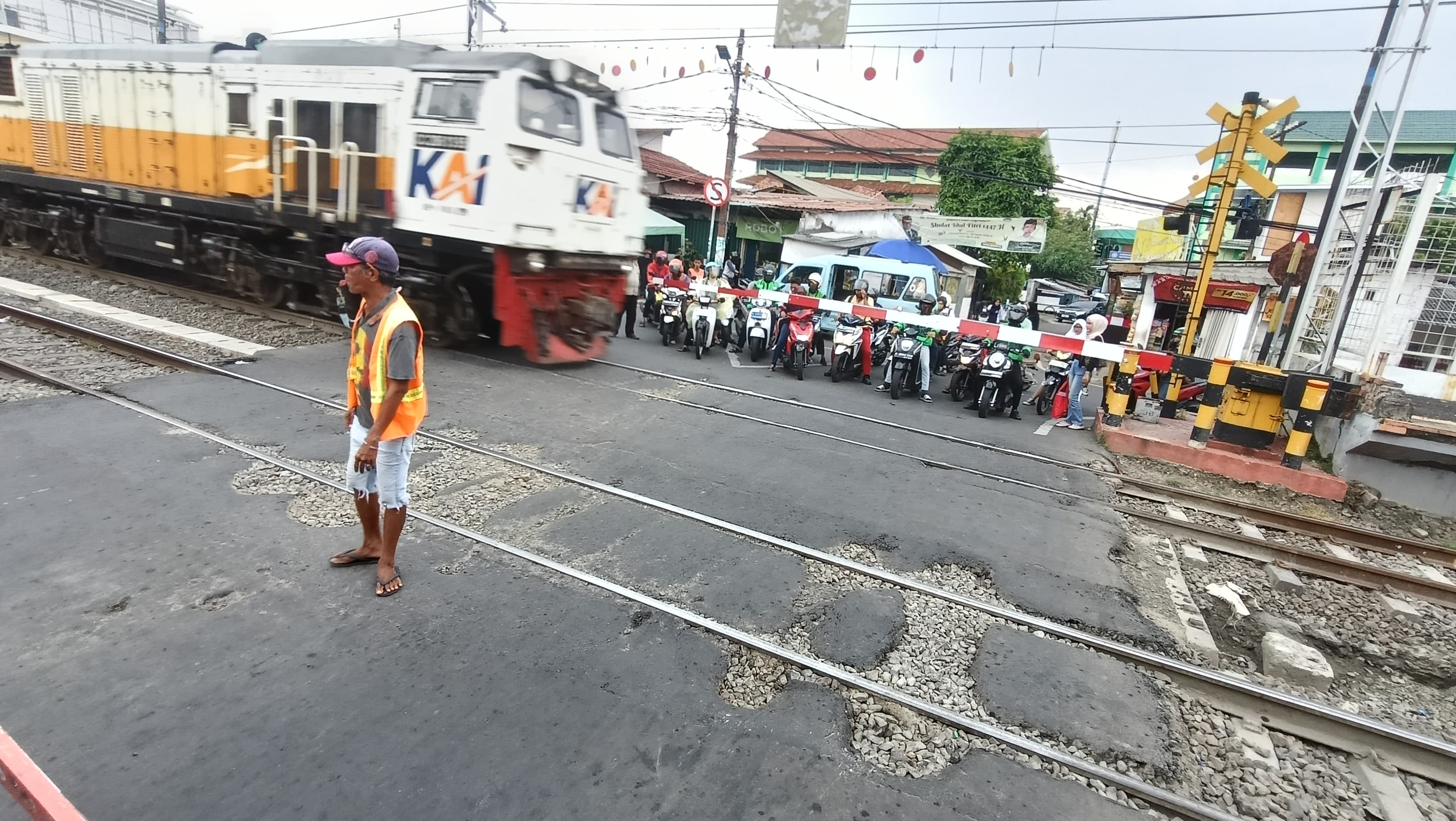 Seorang warga mengatur lalu lintas penyebarangan di perlintasan sebidang Pondok Jati Jaktim (BeritaNasional/Oke Atmaja)