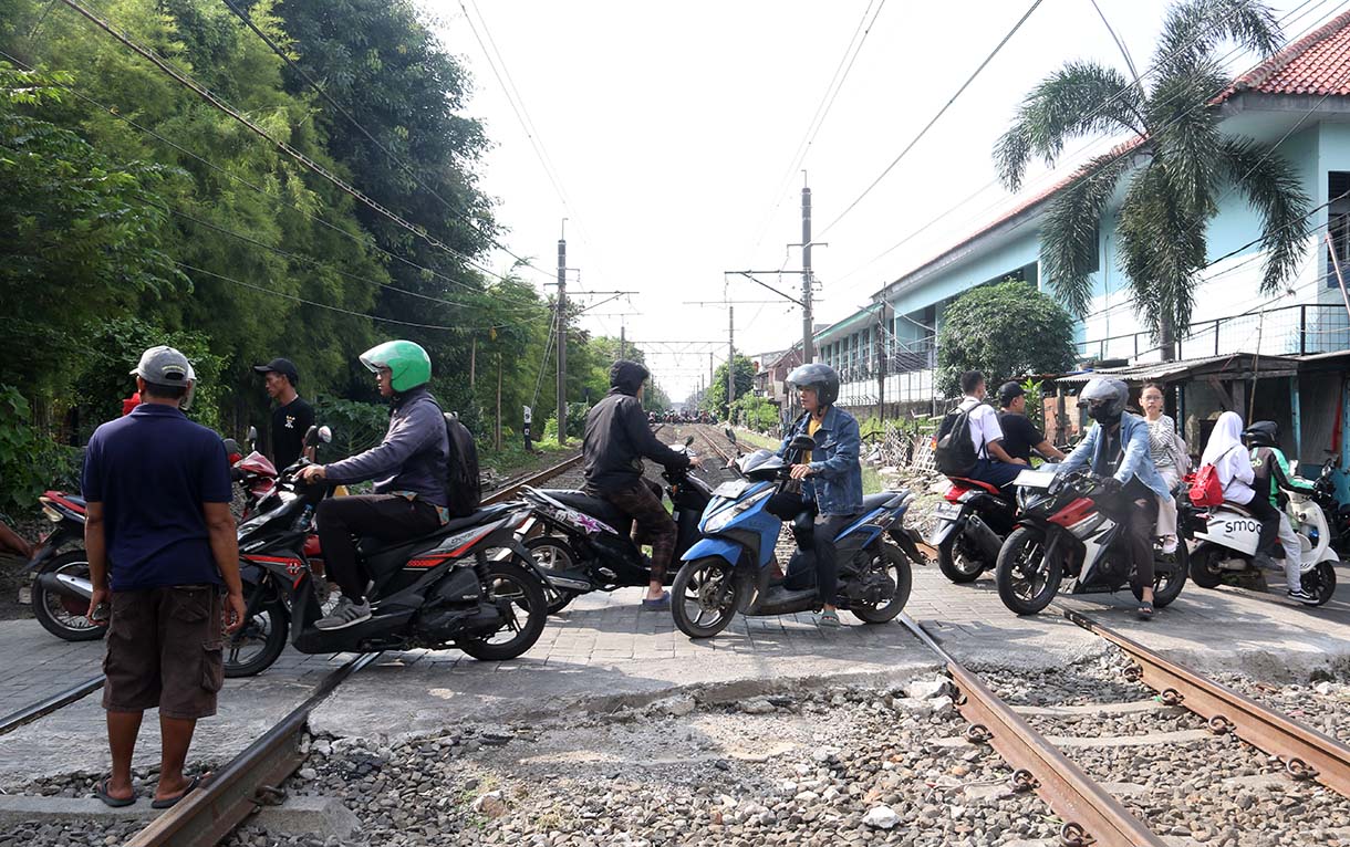 Warga dan pengendara motor melintasi perlintasan sebidang di kawasan Tebet Timur, Jakarta, Selasa (19/5/2026).  (Beritanasional.com/Oke Atmaja)