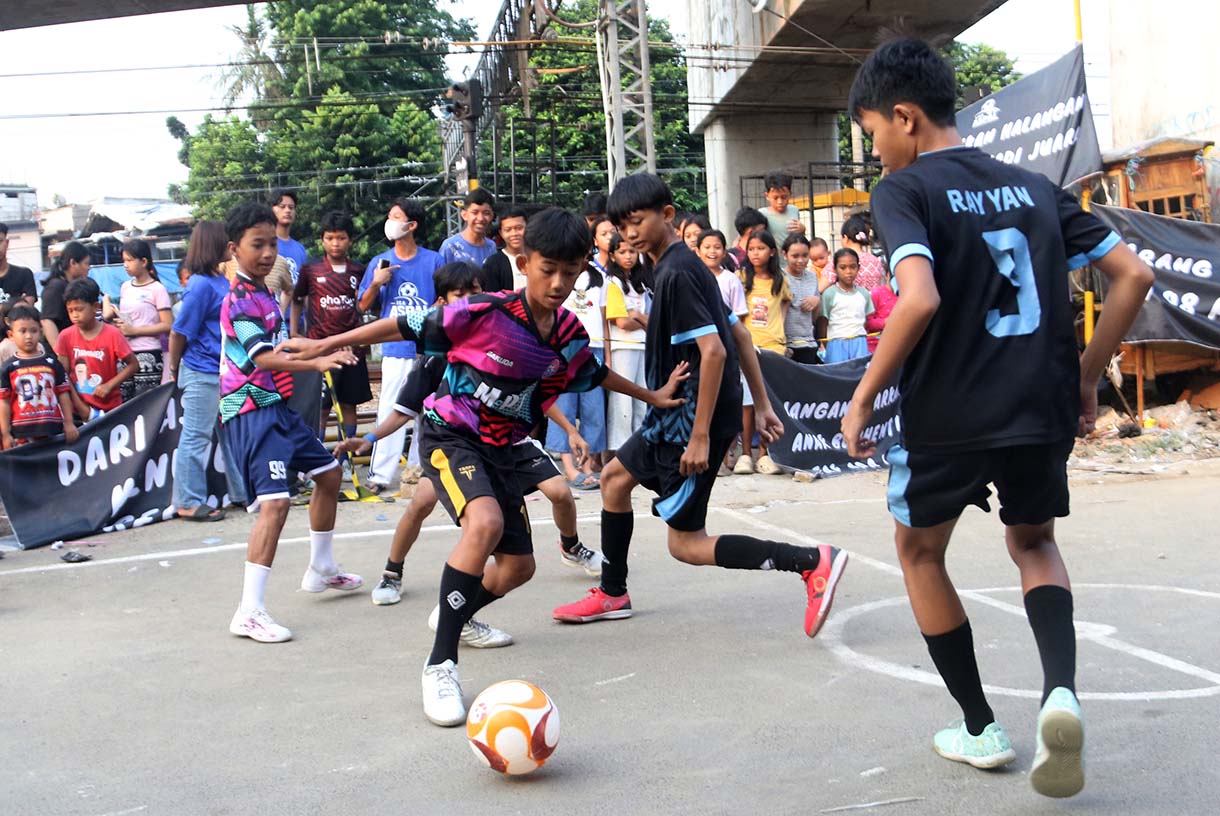 Anak-anak mengikuti pertandingan Turnamen Sepak Bola "Liga Aspal" U-13 di lapangan sederhana kawasan permukiman padat pinggir rel RT 09/RW 08, Menteng Jaya, Jakarta, Sabtu (20/6/2026). (Beritanasional.com/Oke Atmaja)